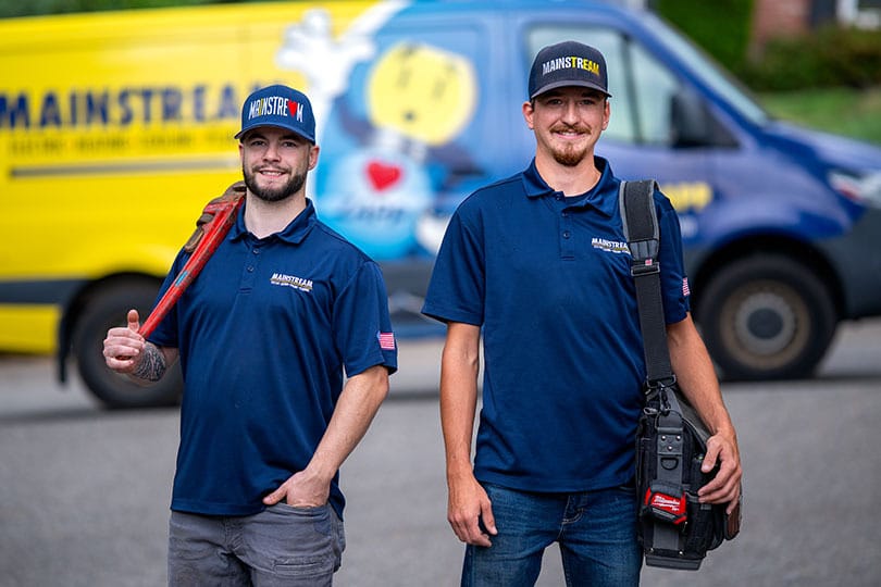Two Mainstream technicians walking together in front of a branded service van